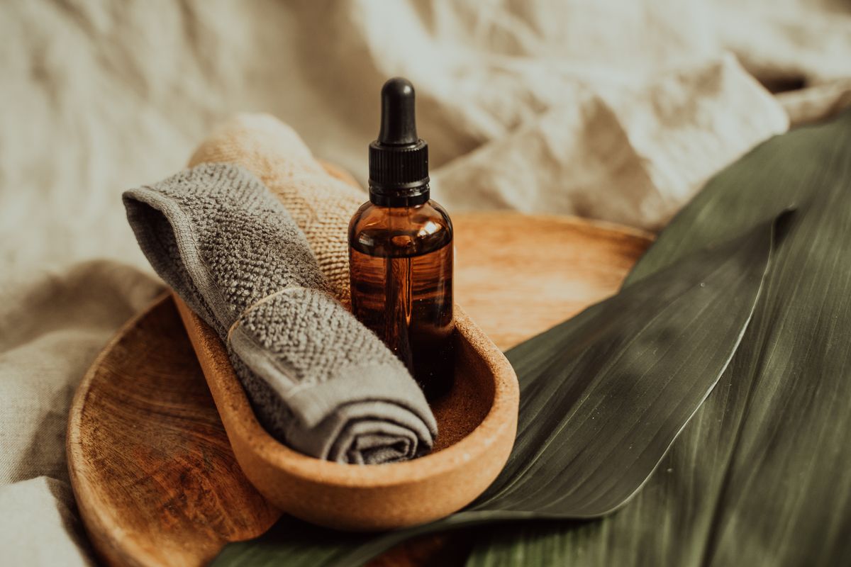 Aceite de masaje, toallas de algodón y accesorios dispuestos sobre una superficie de madera